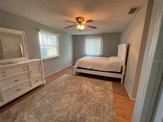 bedroom featuring a textured ceiling, light wood-type flooring, and ceiling fan