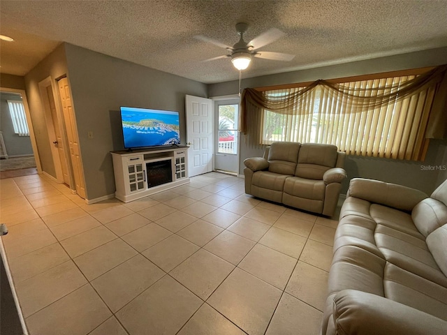 unfurnished living room featuring ceiling fan, a fireplace, light tile patterned floors, and a textured ceiling