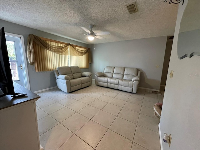 living room featuring ceiling fan, light tile patterned flooring, and a textured ceiling