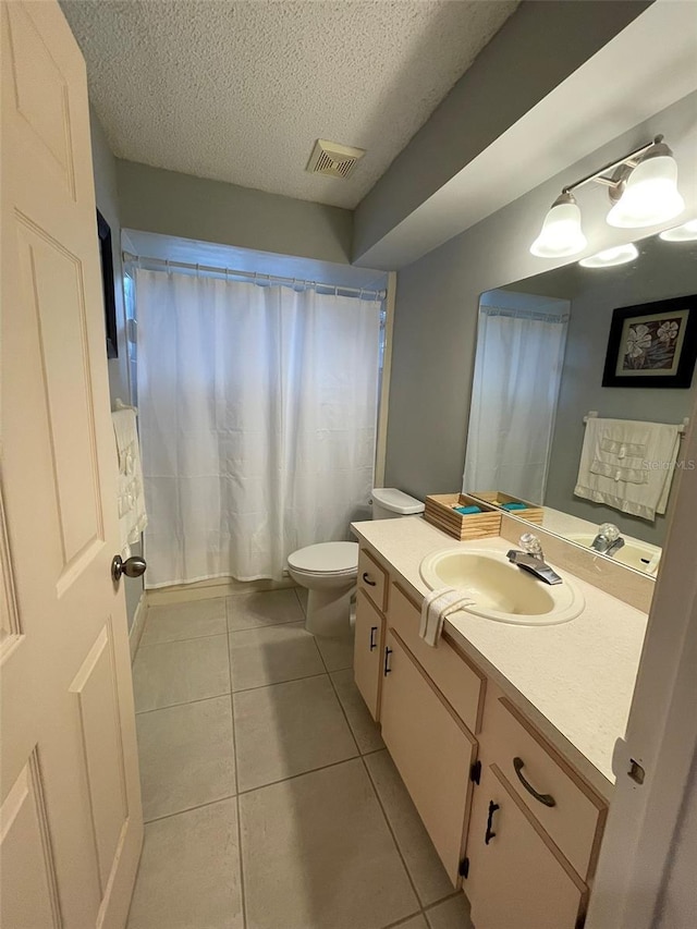 bathroom with tile patterned flooring, vanity, a textured ceiling, and toilet