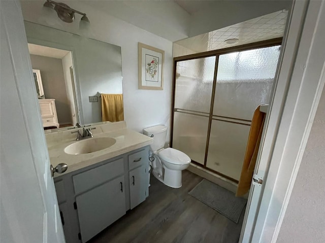 bathroom featuring toilet, a shower with door, vanity, and hardwood / wood-style flooring