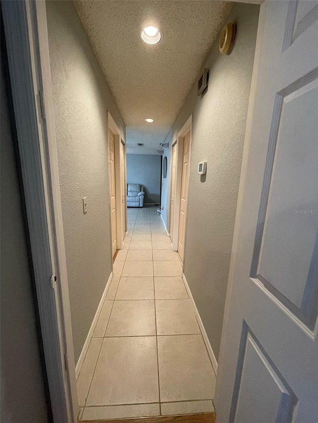 hall featuring light tile patterned floors and a textured ceiling