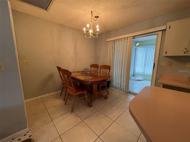 tiled dining space featuring a textured ceiling and a notable chandelier