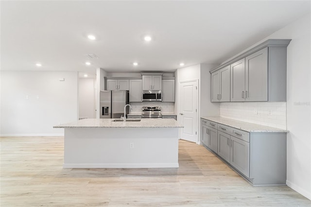 kitchen with gray cabinetry, light stone countertops, sink, and appliances with stainless steel finishes