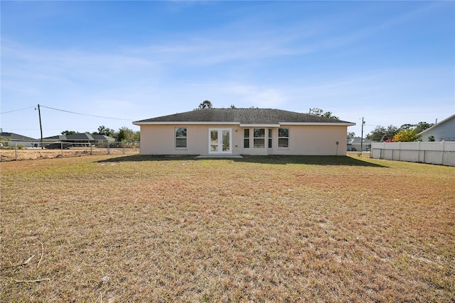 back of property featuring french doors and a lawn