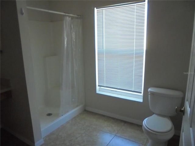 bathroom featuring tile patterned flooring, a wealth of natural light, toilet, and curtained shower