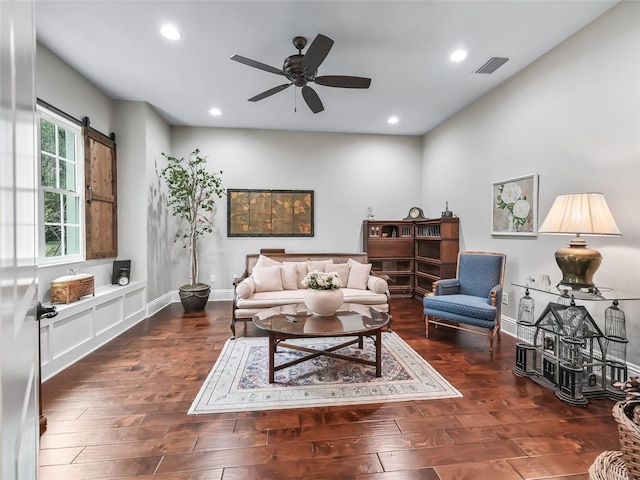 living room with ceiling fan, a barn door, and dark hardwood / wood-style flooring