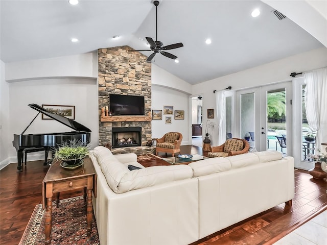 living room featuring ceiling fan, french doors, a stone fireplace, wood-type flooring, and vaulted ceiling