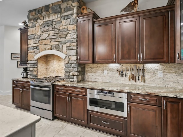 kitchen featuring backsplash, light stone counters, dark brown cabinetry, and stainless steel appliances