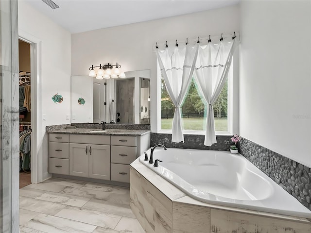 bathroom with vanity and tiled bath