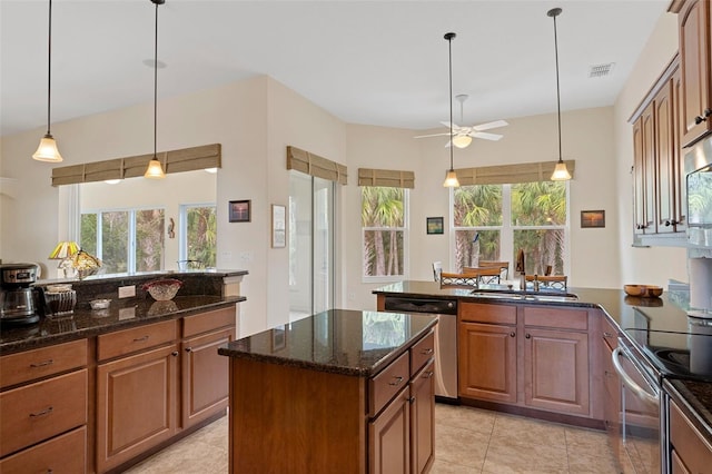 kitchen featuring a center island, sink, ceiling fan, dark stone countertops, and stainless steel appliances