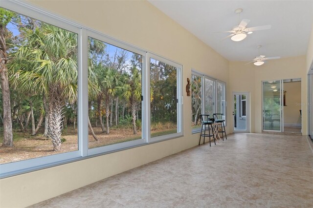 unfurnished sunroom featuring ceiling fan and a healthy amount of sunlight