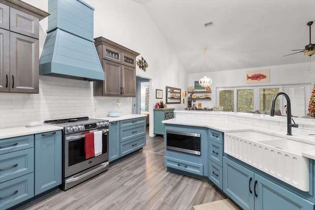 kitchen featuring sink, stainless steel appliances, vaulted ceiling, custom range hood, and light wood-type flooring