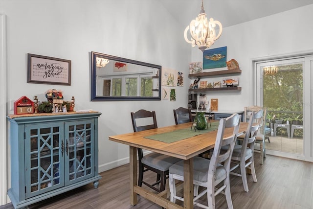 dining space with hardwood / wood-style floors, high vaulted ceiling, and a notable chandelier