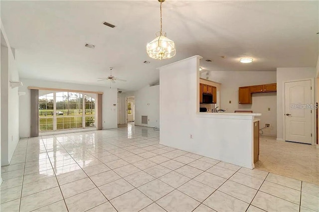 spare room with vaulted ceiling, light tile patterned flooring, and ceiling fan with notable chandelier