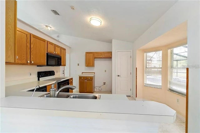 kitchen featuring kitchen peninsula, stainless steel electric range oven, sink, and lofted ceiling