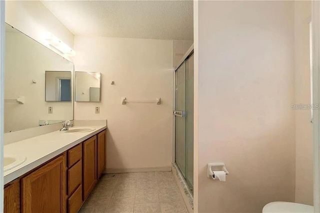 bathroom featuring tile patterned flooring, vanity, a shower with shower door, and a textured ceiling