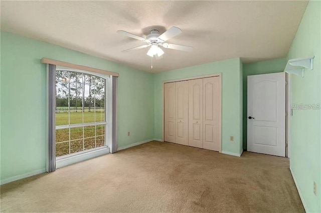 unfurnished bedroom featuring a closet, light colored carpet, and ceiling fan