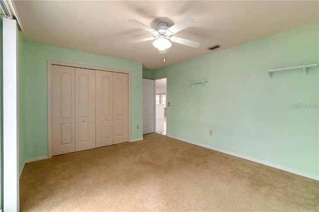 unfurnished bedroom with ceiling fan, a closet, and light carpet