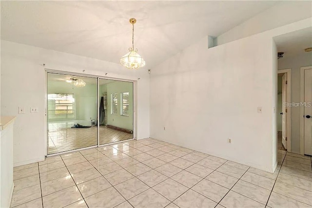 tiled empty room with lofted ceiling and a notable chandelier