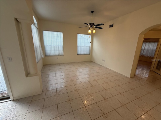 empty room featuring light tile patterned flooring, ceiling fan, and a healthy amount of sunlight