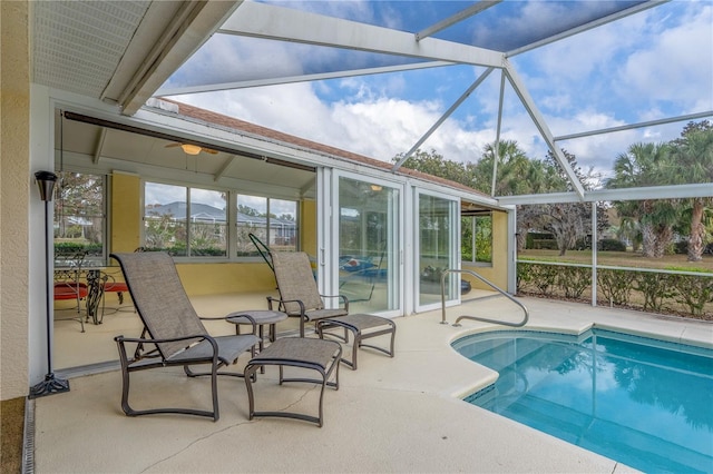 view of swimming pool featuring glass enclosure, ceiling fan, a patio area, and a mountain view