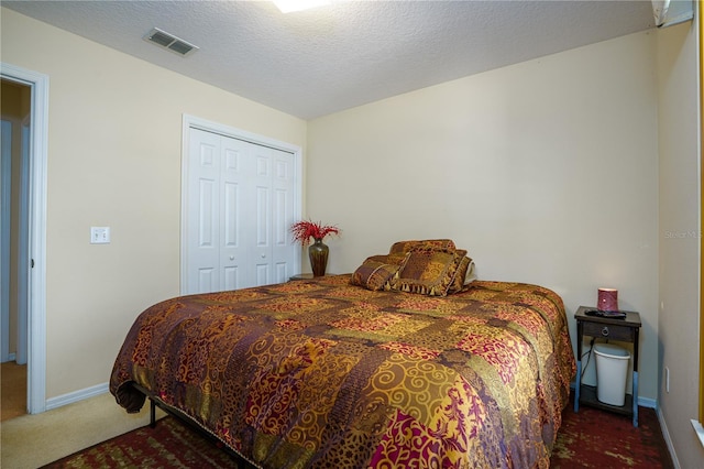 bedroom with a closet, carpet floors, and a textured ceiling