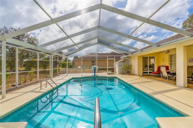 outdoor pool featuring glass enclosure, a patio, fence, and a ceiling fan