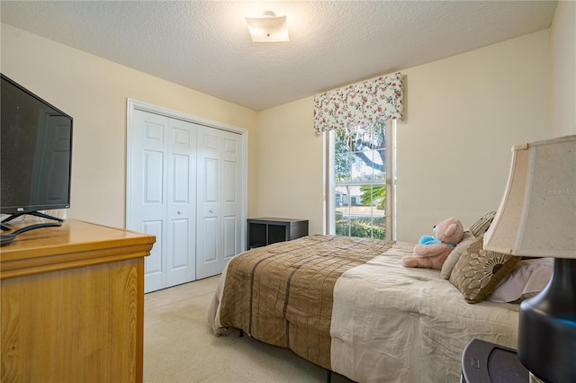 bedroom featuring light carpet, a textured ceiling, and a closet