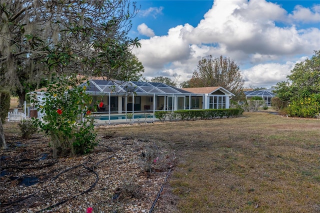 back of property with glass enclosure, a yard, and an outdoor pool