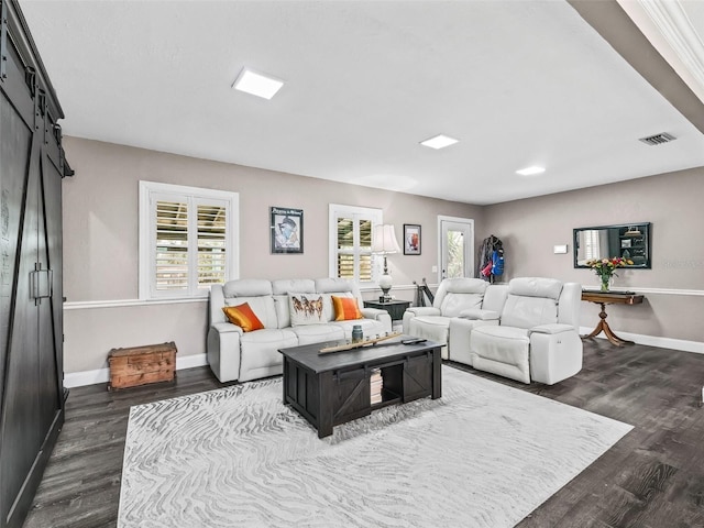 living room with a barn door, a wealth of natural light, and dark wood-type flooring