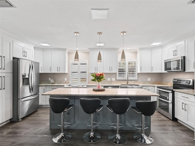 kitchen with a center island, hanging light fixtures, and appliances with stainless steel finishes