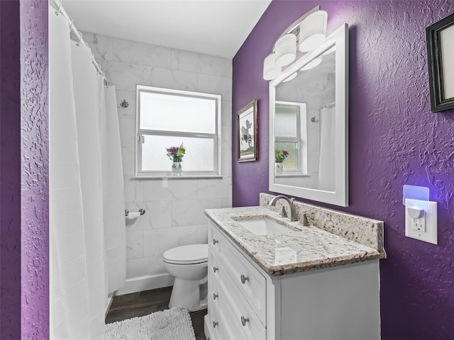 bathroom featuring vanity, tile walls, and toilet