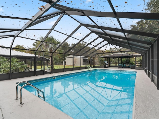 view of pool with glass enclosure, an outdoor living space, and a patio