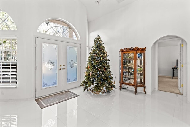 tiled foyer entrance featuring a towering ceiling and french doors