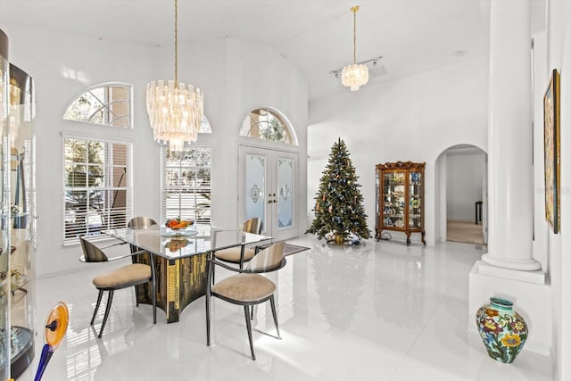 dining space with a notable chandelier, decorative columns, high vaulted ceiling, and french doors