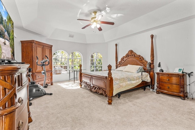 bedroom featuring ceiling fan, light carpet, and a tray ceiling