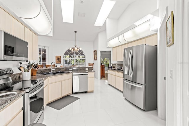 kitchen featuring sink, stainless steel appliances, decorative light fixtures, vaulted ceiling with skylight, and light tile patterned floors