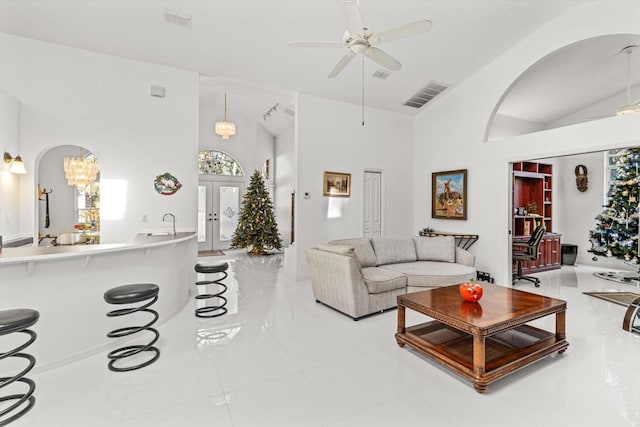 living room featuring ceiling fan with notable chandelier, light tile patterned floors, high vaulted ceiling, and french doors