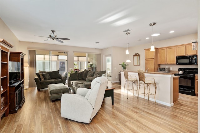 living room with ceiling fan and light hardwood / wood-style floors