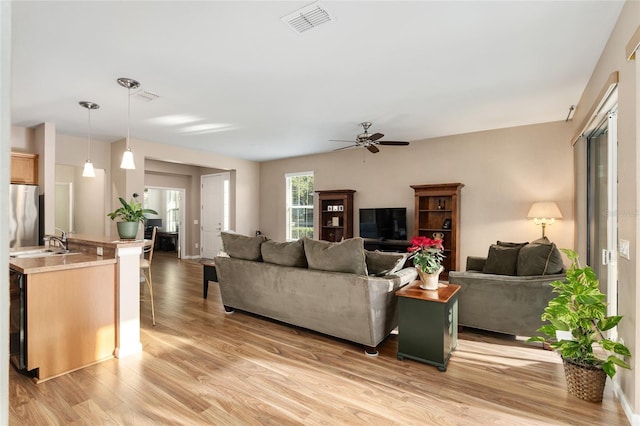 living room featuring hardwood / wood-style flooring, ceiling fan, and sink