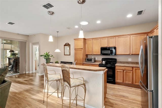 kitchen featuring a center island, decorative light fixtures, light hardwood / wood-style flooring, and black appliances