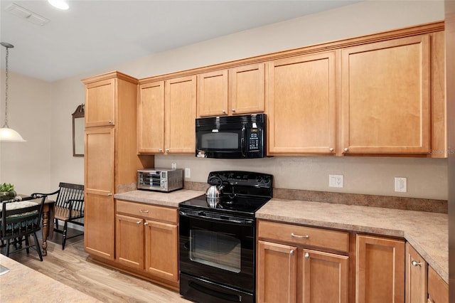 kitchen with decorative light fixtures, light hardwood / wood-style floors, and black appliances