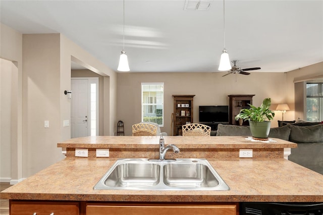 kitchen featuring a center island with sink, decorative light fixtures, ceiling fan, and sink