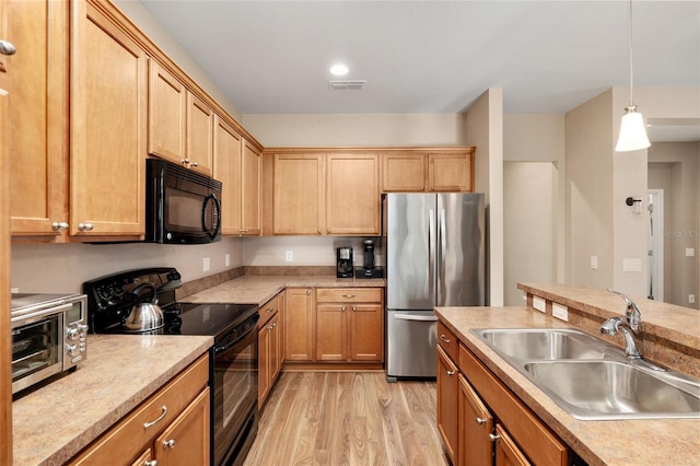 kitchen with light wood-type flooring, sink, decorative light fixtures, and black appliances