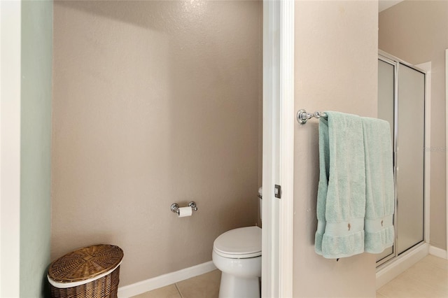 bathroom featuring tile patterned flooring, toilet, and a shower with door