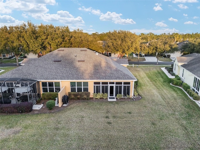 rear view of property with a lanai and a yard