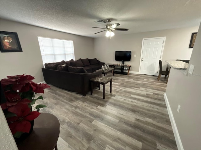 living room with hardwood / wood-style floors, a textured ceiling, and ceiling fan