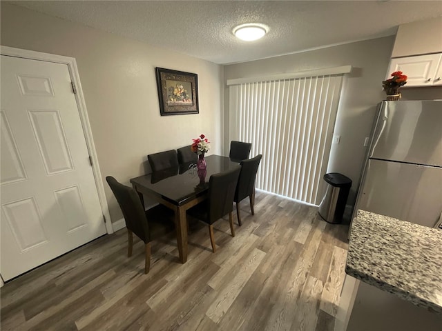 dining room with hardwood / wood-style floors and a textured ceiling