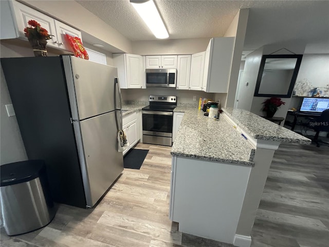 kitchen featuring kitchen peninsula, appliances with stainless steel finishes, a textured ceiling, white cabinets, and light hardwood / wood-style floors